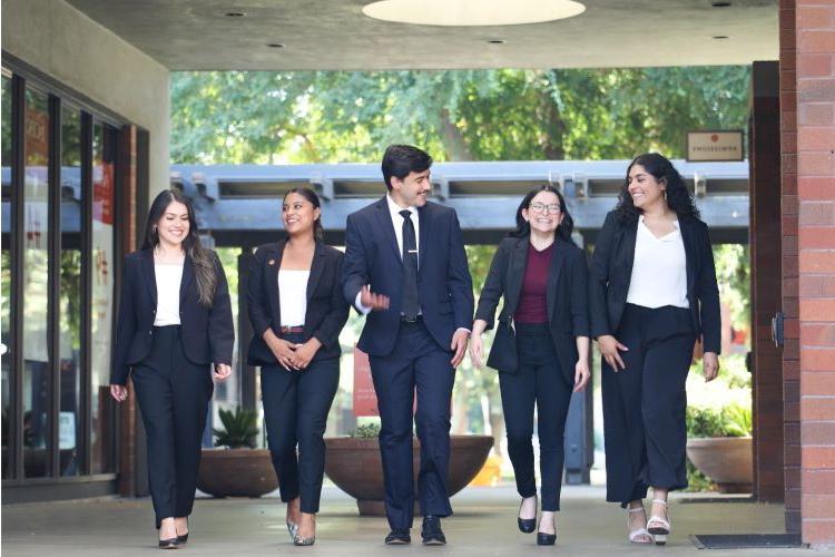 (从左至右)麦克乔治大学的学生Perla Ornelas-Perez, Devynn代理, 扫罗Vargas, 纳塔莉亚Osorio-Elizondo, 和艾丽卡·阿尔瓦雷斯·拉莫斯走过萨克拉门托校园的走廊. 这些学生是拉丁裔法律学生协会的成员.